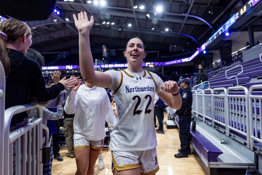 Northwestern's Grace Sullivan smiles and high fives fans as she walks off the court after a win.