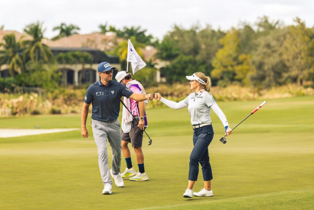 Corey Conners and Brooke Henderson fist bump and a caddie replaces the flag in the background