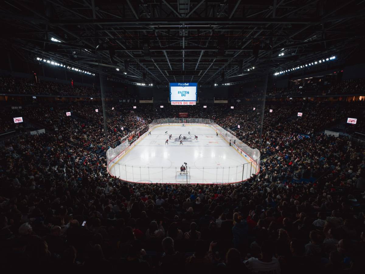 A wide-angle shot of the ice from behind Desbiens' net. The ice appears far away and the packed stands are also visible.