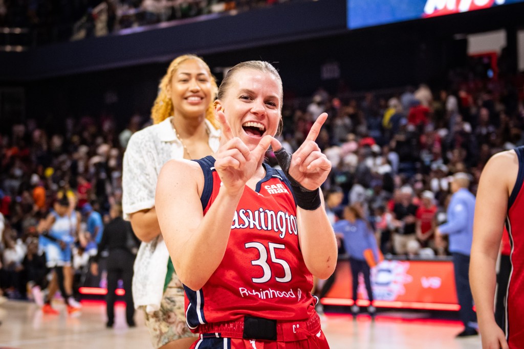 Washington Mystics guard Julie Vanloo smiles at the camera and makes a "W" sign with her hands after a win.
