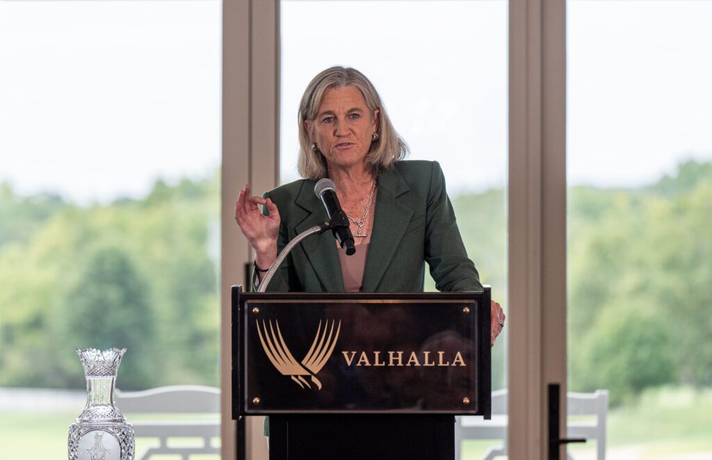 Former LPGA Commissioner Mollie Marcoux Samaan speaks at a podium at Valhalla Golf Club and gestures with her right hand.