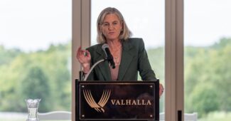 Former LPGA Commissioner Mollie Marcoux Samaan speaks at a podium at Valhalla Golf Club and gestures with her right hand.
