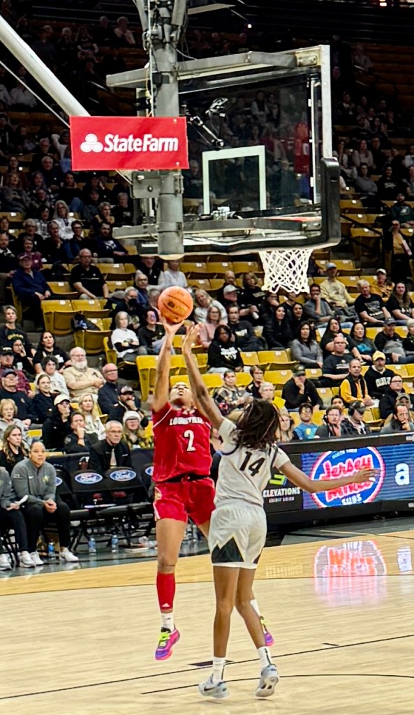 Louisville guard Nyla Harris shoots under the basket and is challenged by a Colorado player at a basketball game played at the Colorado Special Events Center.