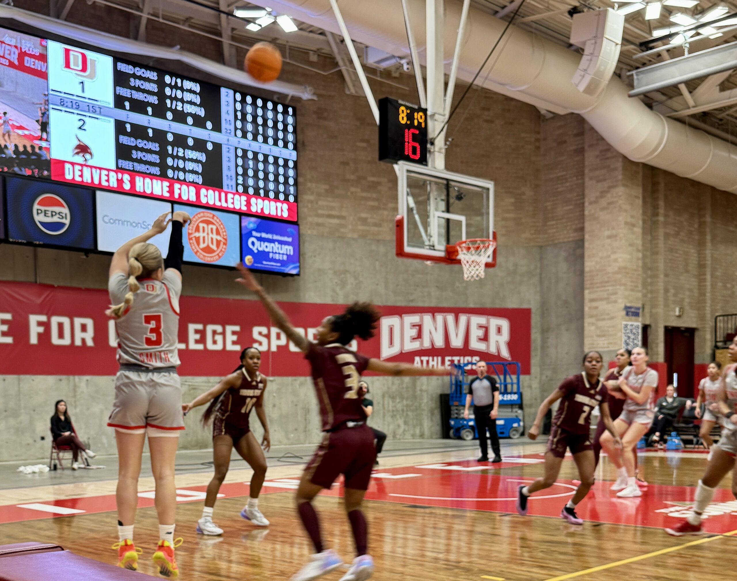 Emma Smith shoots a high arching shot over a Texas State basketball player at Hamilton Gymnasium in Denver.