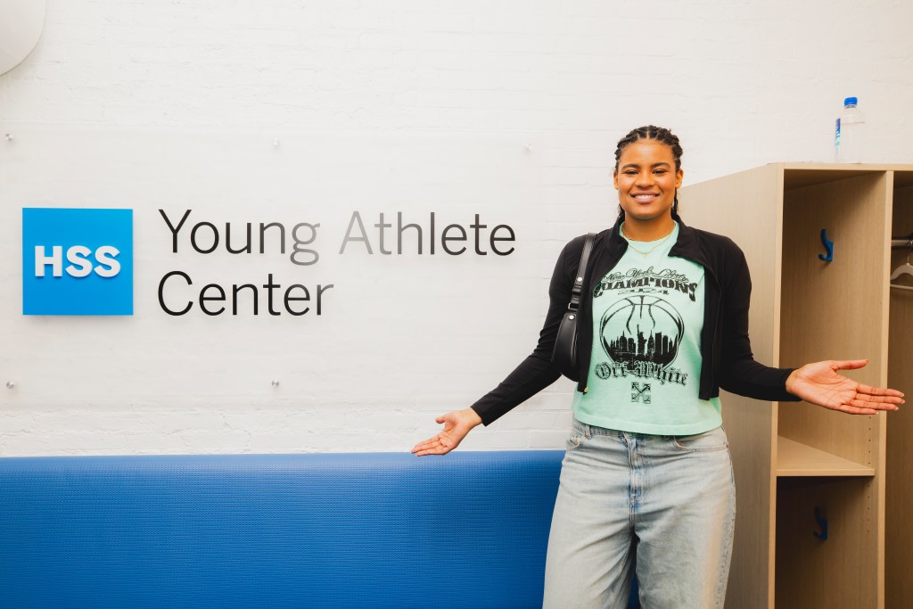 Nyara Sabally stands in front of a sign that says Young Athlete Center