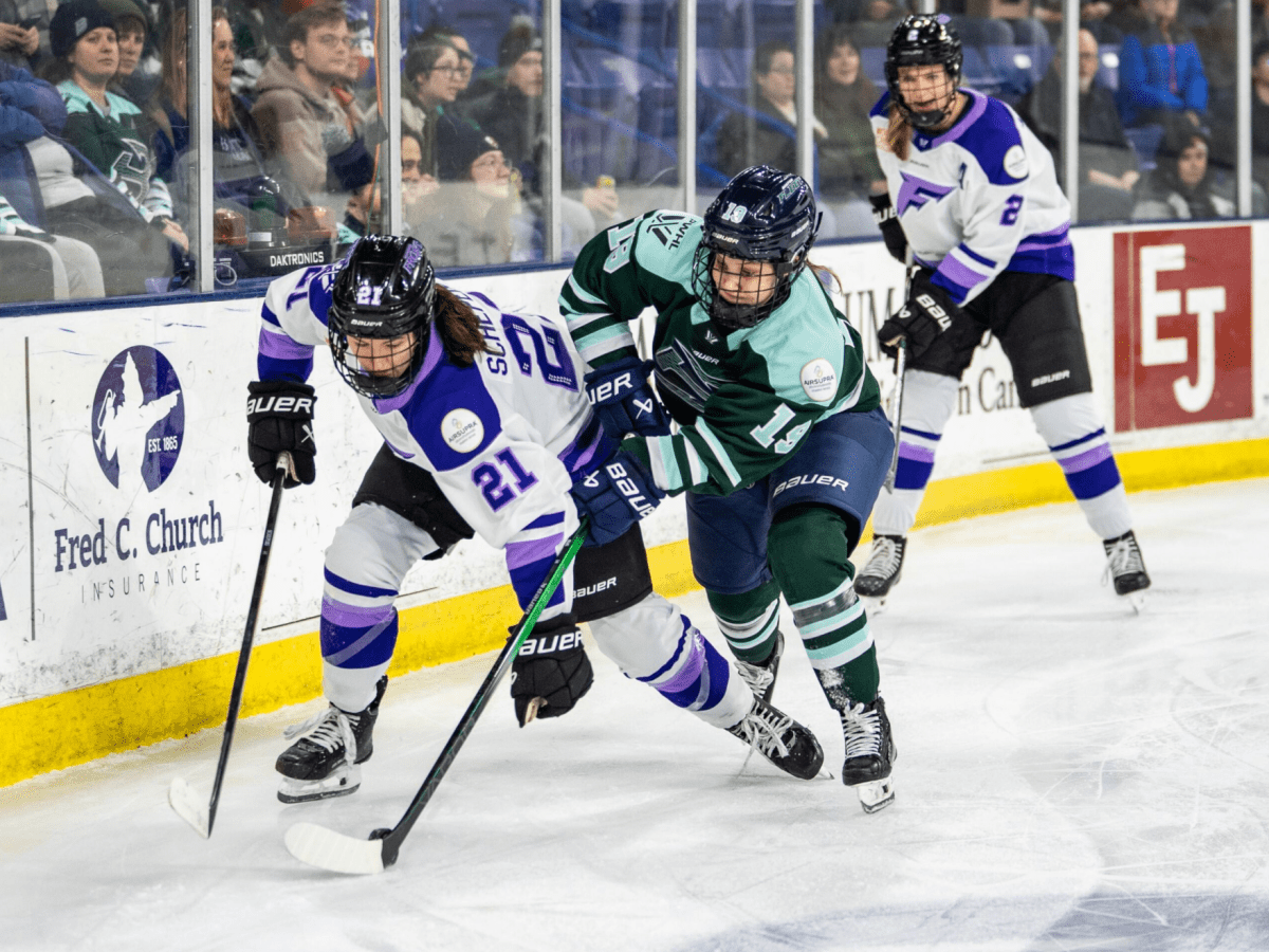 Bilka (right in green) and Schepers (left in white) battle for the puck along the boards.