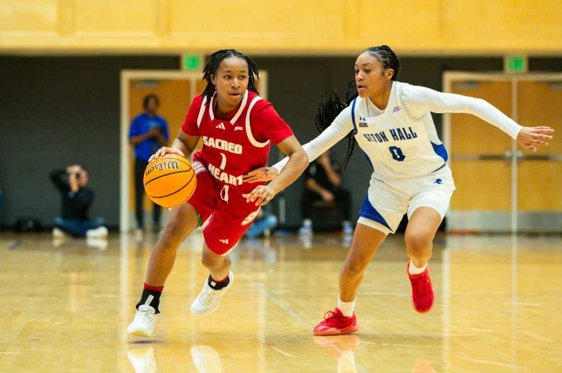 Ny'Ceara Pryor (in red) dribbles the ball upcourt with her right hand as she looks ahead.