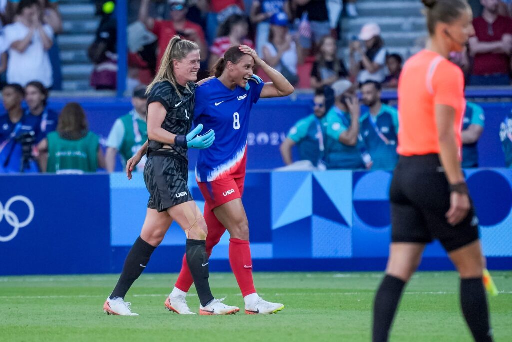 Alyssa Naeher and Lynn Williams celebrate on the field at the 2024 Paris Olympics for the USWNT.