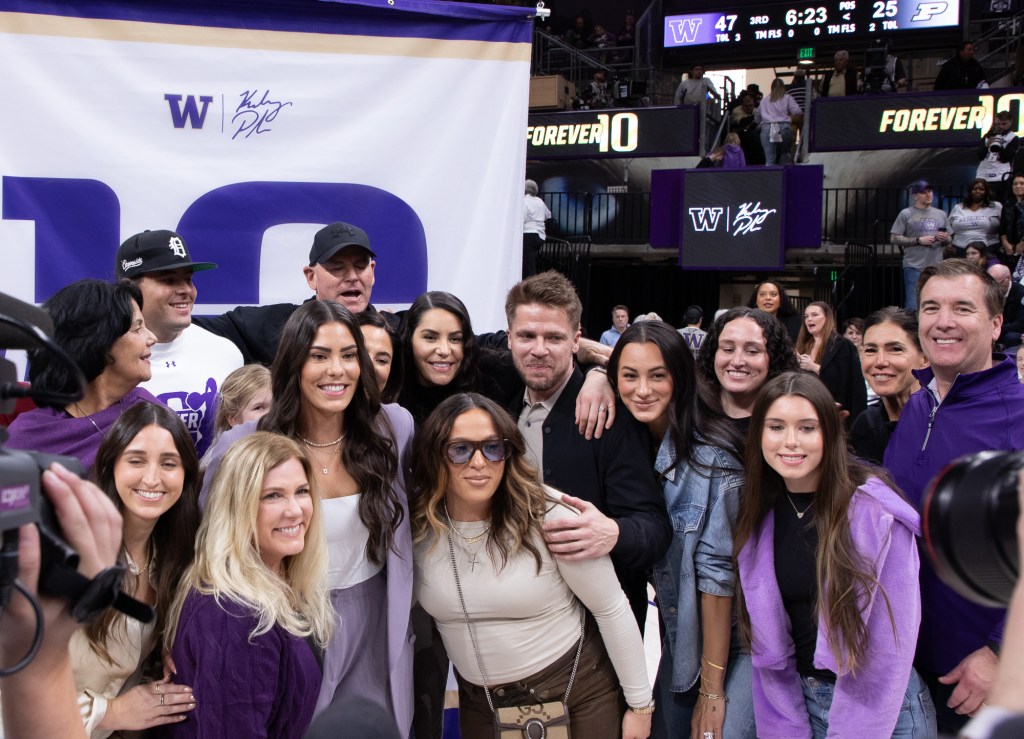 Kelsey Plum poses with a large group of friends and family in front of the Forever 10 banner after her jersey retirement ceremony.
