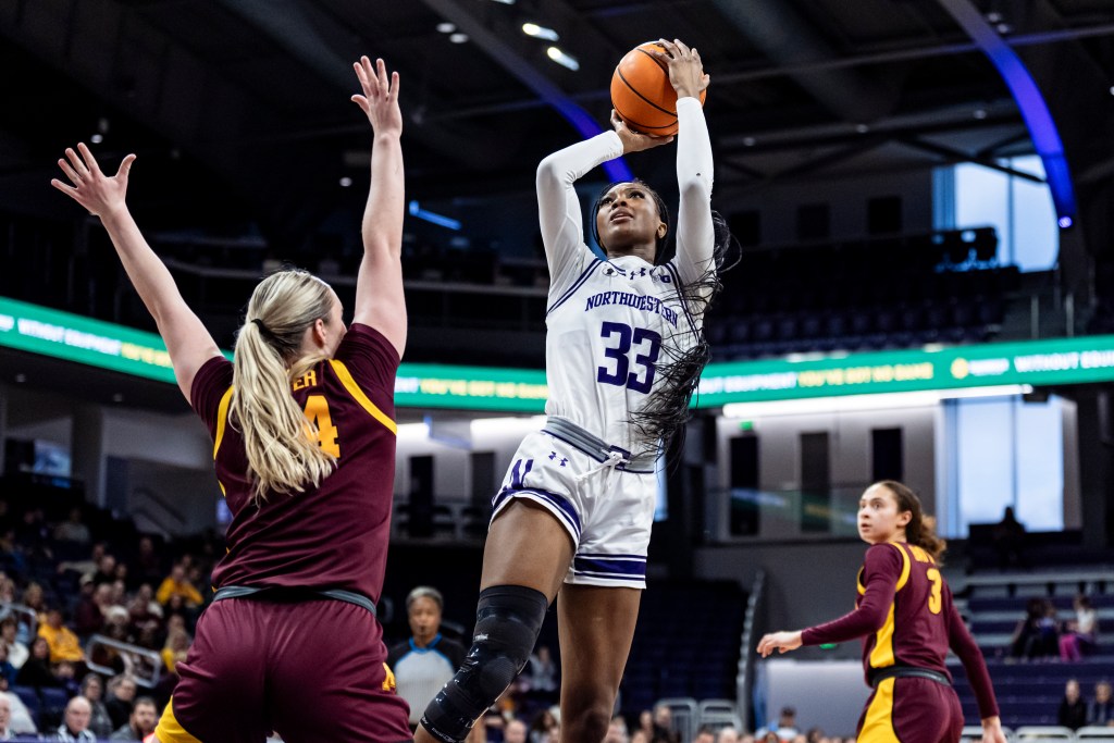 Taylor Williams leans back to shoot a jump shot over a defender with her hand raised