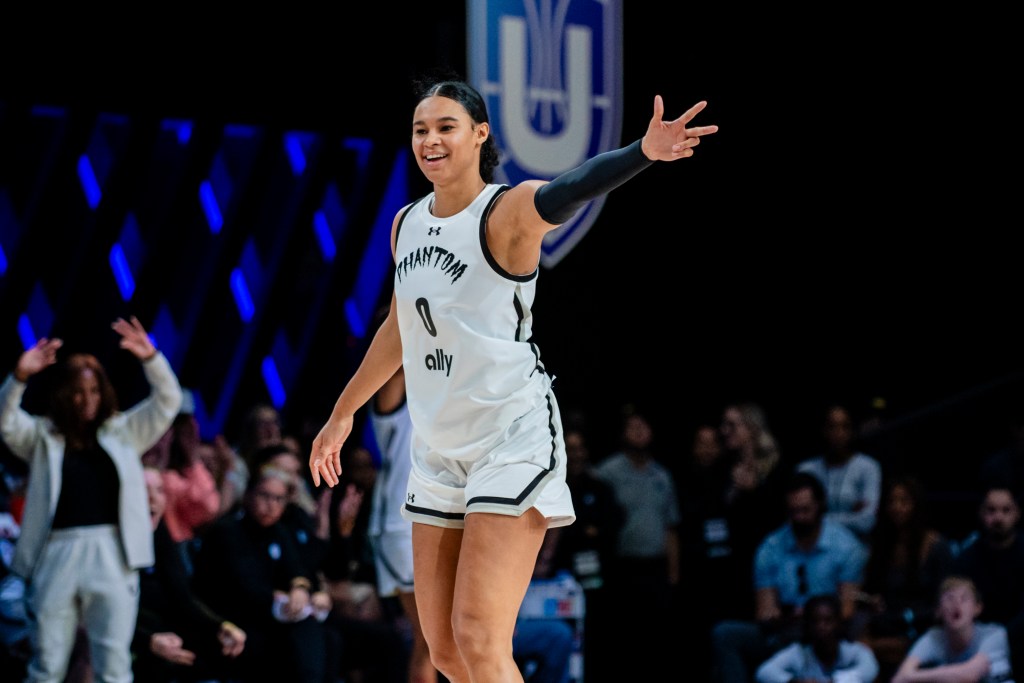 A woman in basketball uniform celebrates on the court