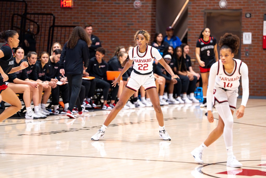 Harvard guards Saniyah Glenn-Bello and Harmoni Turner stand near halfcourt on defense, waiting for a Northeastern ball-handler (who is not pictured) to get closer.