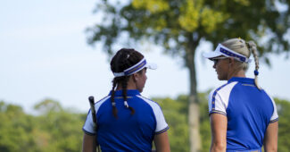 Charley Hull stands to the right of Georgia Hall. Their backs face the camera as they discuss a shot during the Solheim Cup.