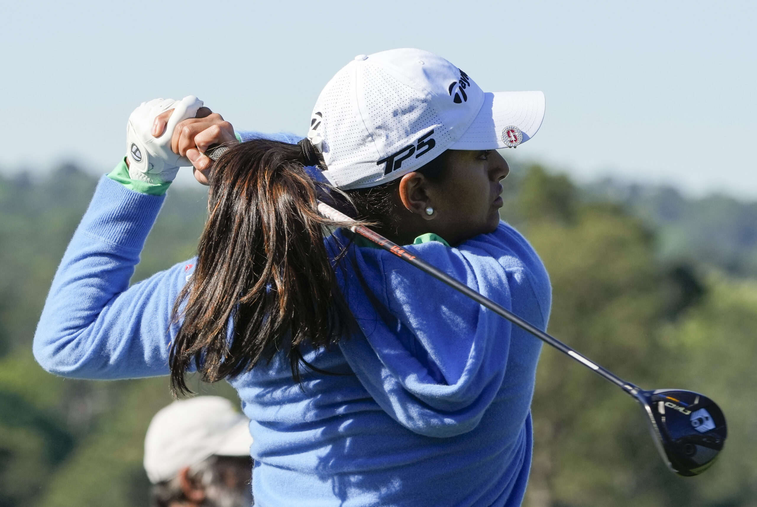 A close up of Megha Ganne as she follows through on a drive. She faces toward the right and the club is in the finished position on her shoulders.