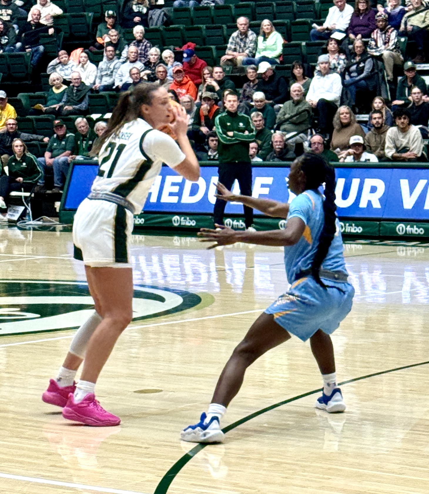 A Colorado State basketball player holds the ball just beyond the arc while a defender from Southern University carefully guards her.