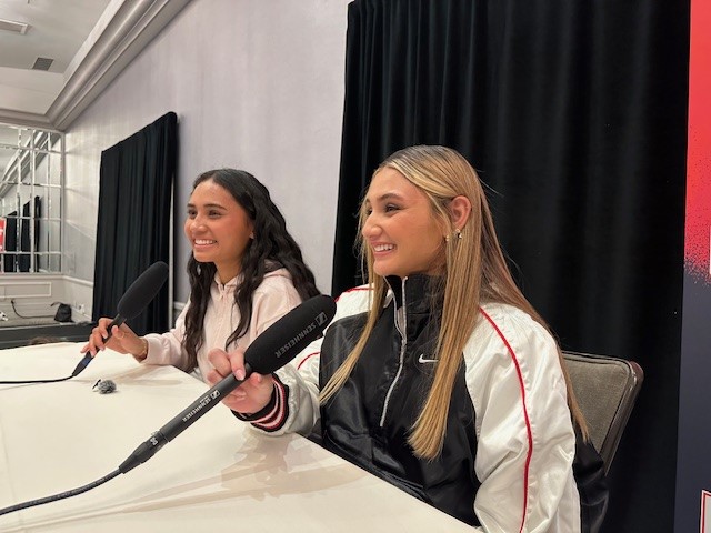 Two women sit in front of microphones