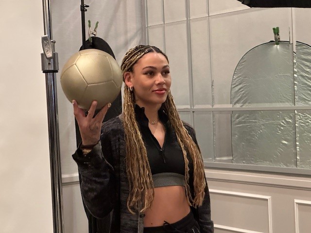 A woman holds a golden soccer ball