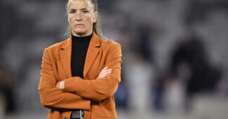 Casey Stoney stands and watches a game as coach
