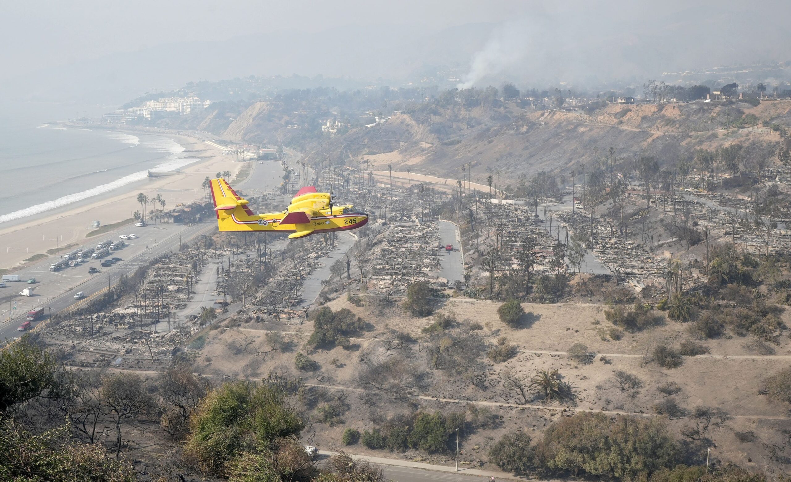 A plane flies over damaged territory in Los Angeles