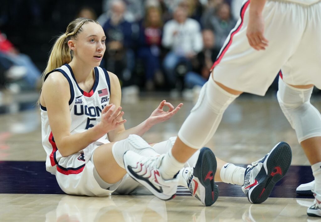 Paige Bueckers gets helped up by her teammates.