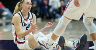 Paige Bueckers gets helped up by her teammates.