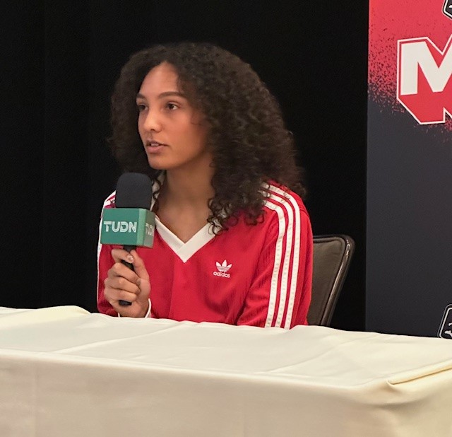 A woman mid-sentence speaks into a microphone