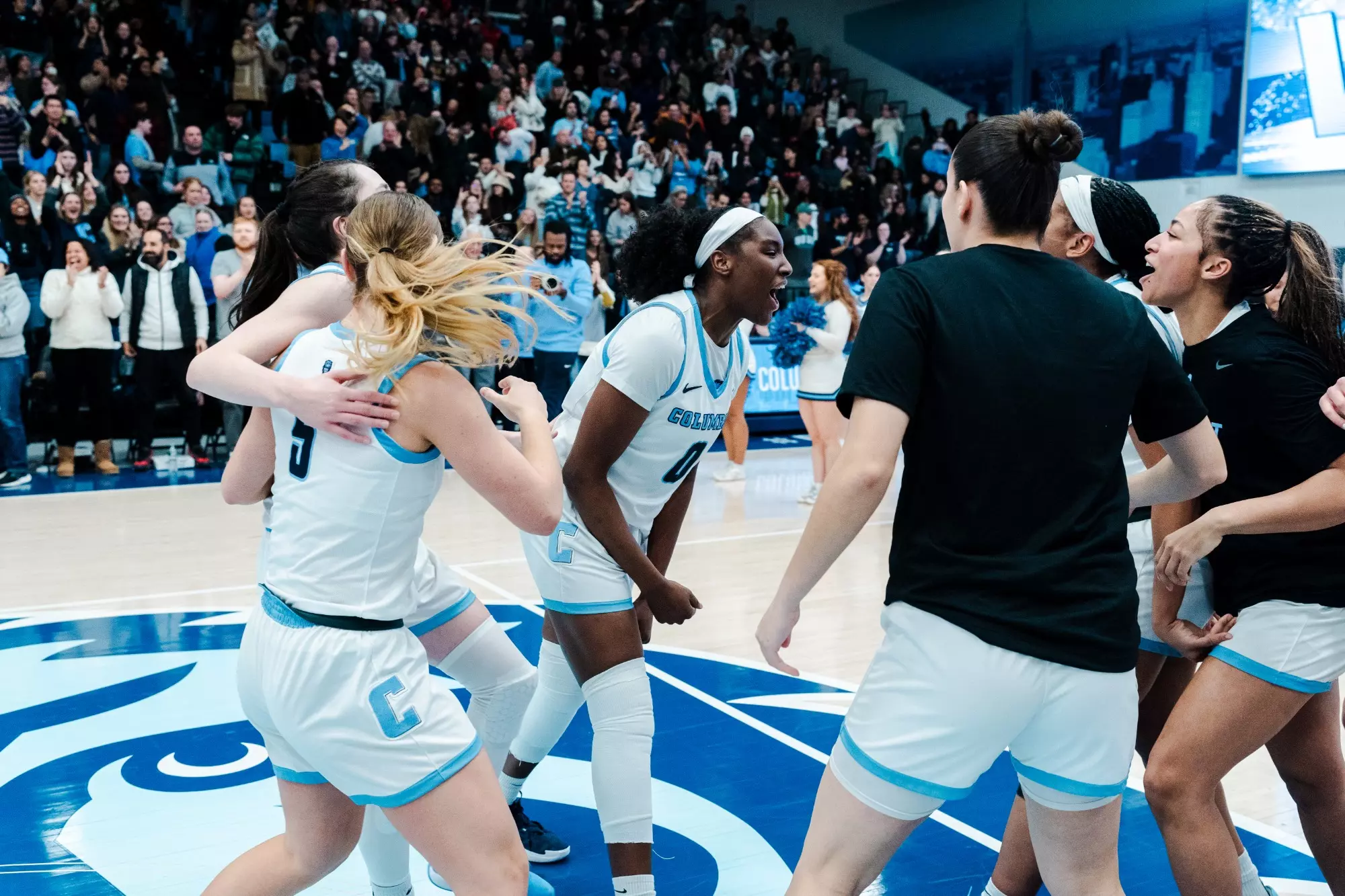 Columbia players gather on the Lions logo at center court to celebrate a home win against Princeton.