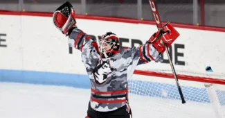 Northeastern netminder Lisa Jönsson celebrates in the home net with her arms over her head.