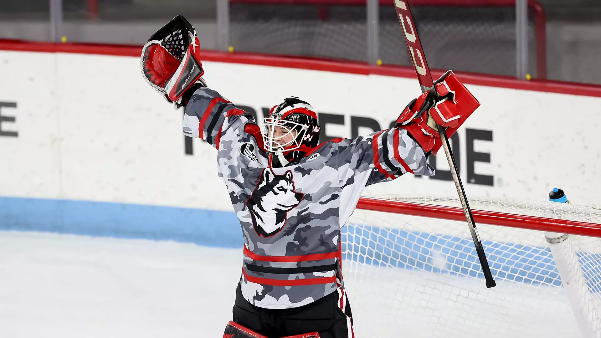 Northeastern netminder Lisa Jönsson celebrates in the home net with her arms over her head.