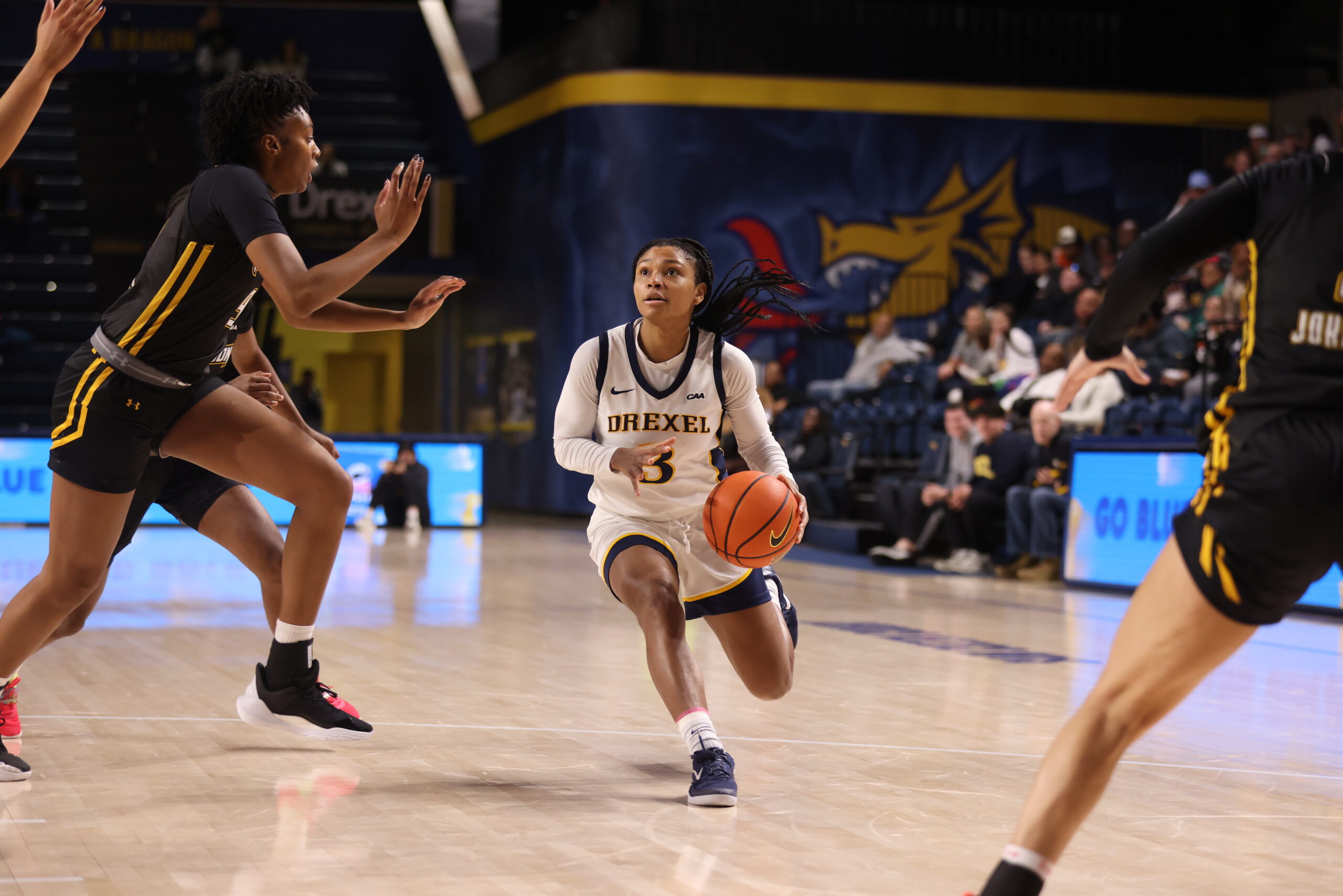 Drexel's Amaris Baker splits a pair of Towson defenders and dribbles inside the arc.