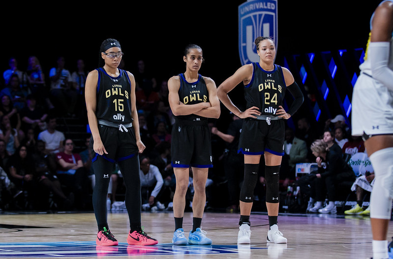 Allisha Gray stands to the left od Unrivaled teammates on the Lunar Owls Skylar Diggins and Napheesa Collier while an opponent shoots a free throw