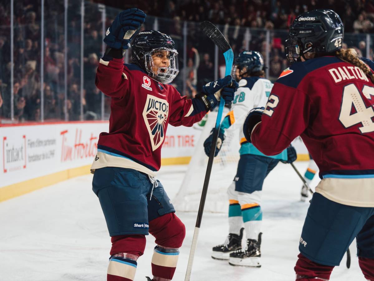 Grant-Mentis raises her arms in celebration, as Dalton skates in for the hug. They are wearing maroon home uniforms.