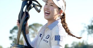 Yealimi Noh holds up the Founders Cup trophy to her right side while smiling broadly.