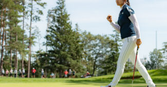 A Lim Kim strides toward the hole and fist pumps to celebrate making a putt.