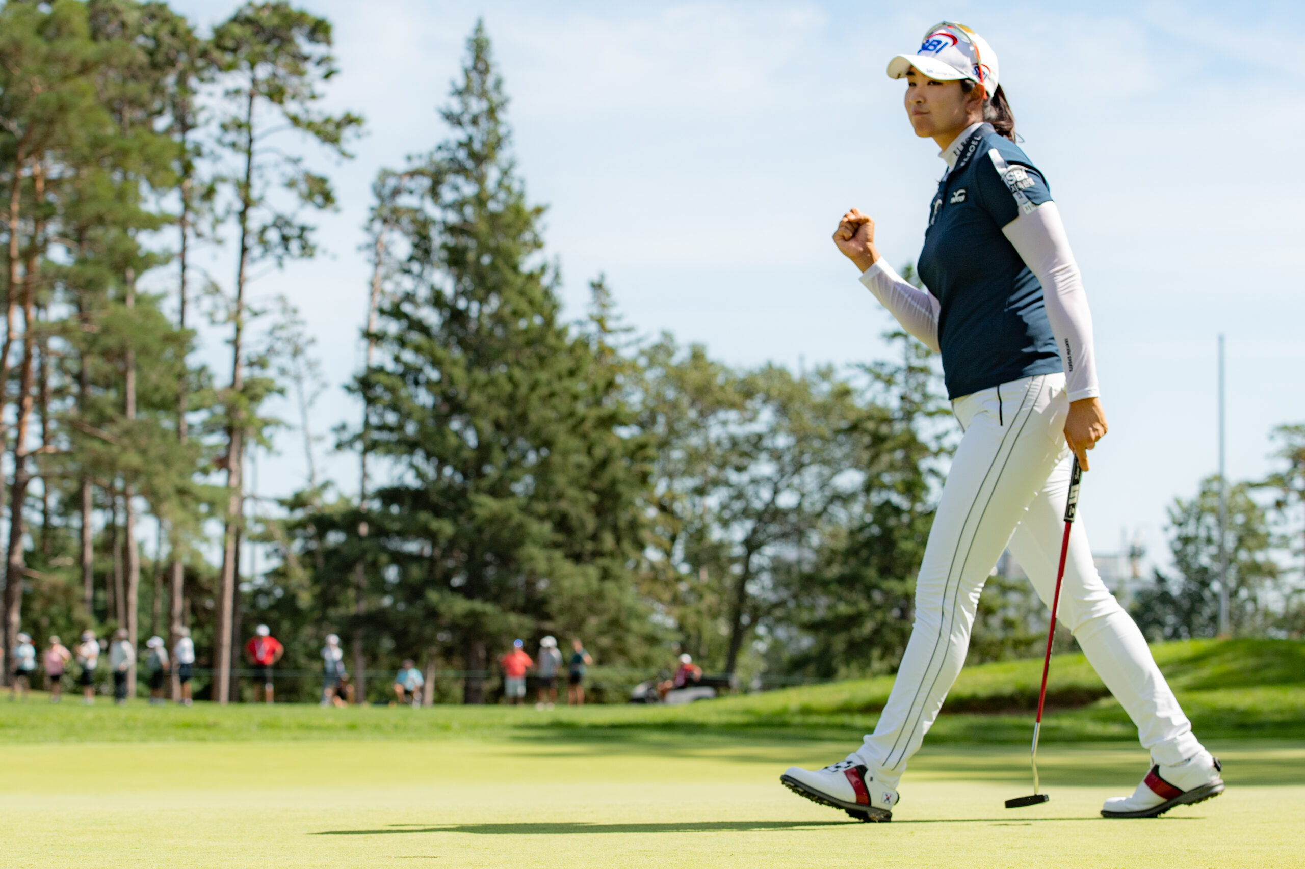 A Lim Kim strides toward the hole and fist pumps to celebrate making a putt.