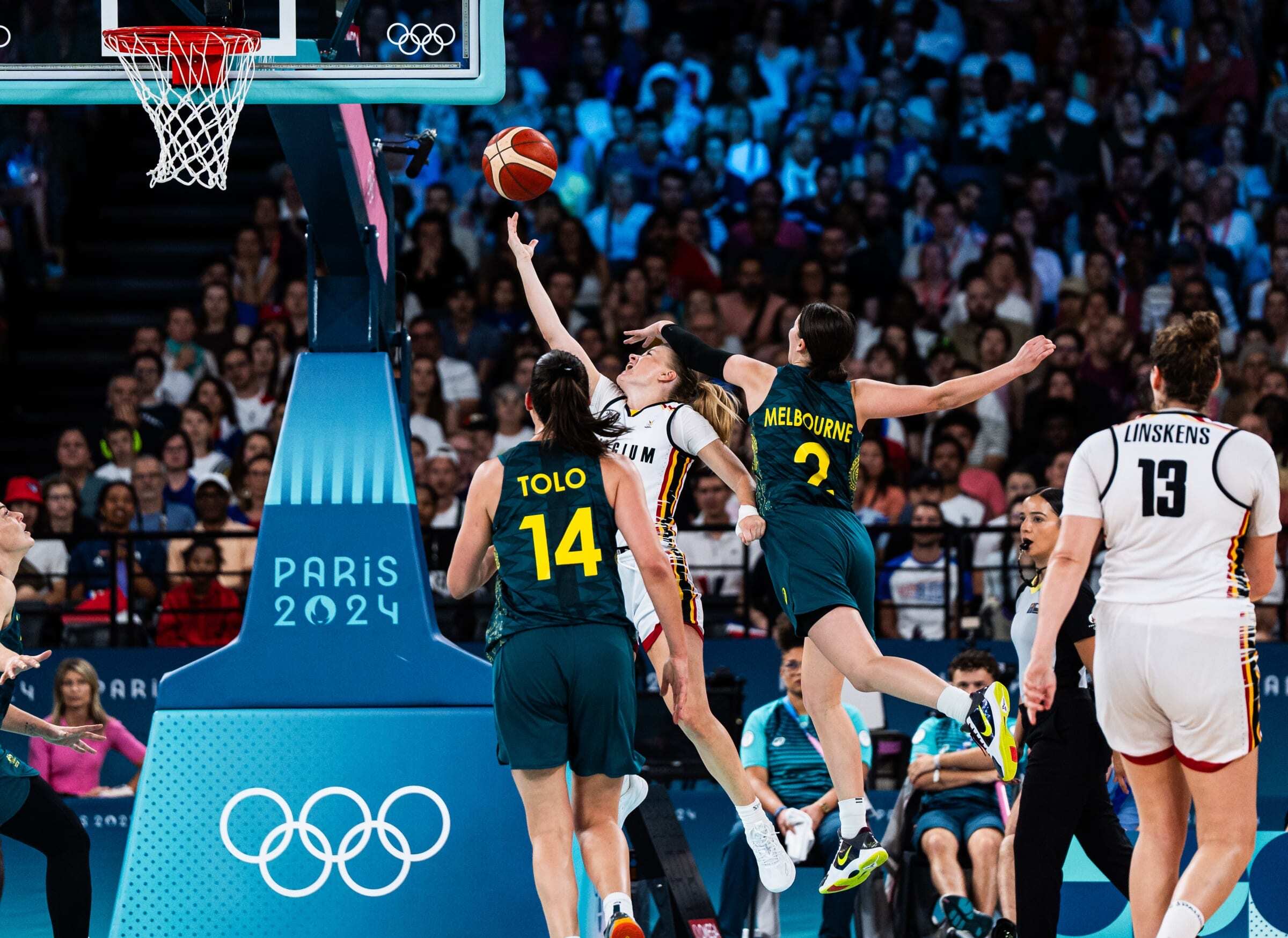 Belgium guard Julie Vanloo attempts a right-handed layup as Australia guard Jade Melbourne reaches across Vanloo's body from behind to try to block it.