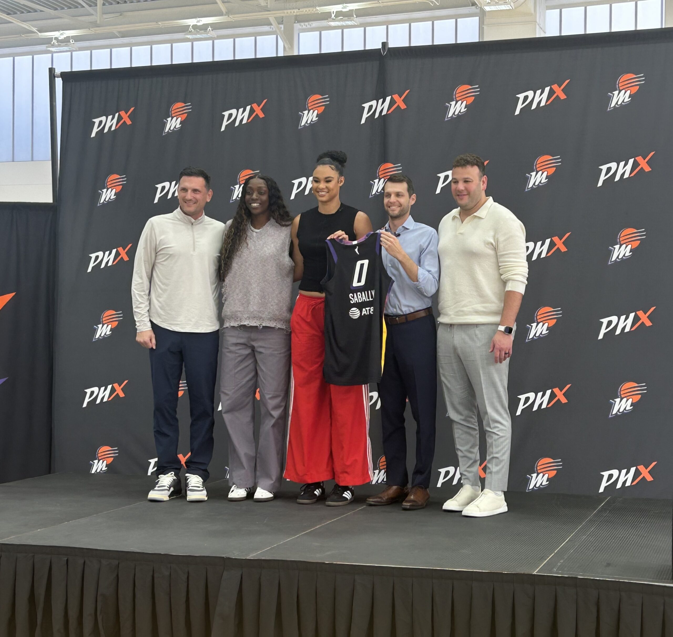 Phoenix Mercury forward Satou Sabally (middle) stands with (from left to right) head coach Nate Tibbetts, Mercury wing Kahleah Copper, General Manager Nick U'Ren and CEO Josh Bartelstein while holding a Satou Sabally Phoenix Mercury jersey (0).