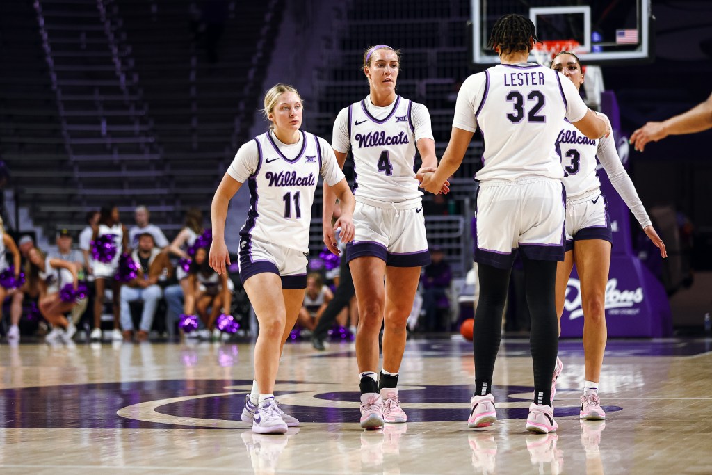 Kansas State players high-five each other on the court.