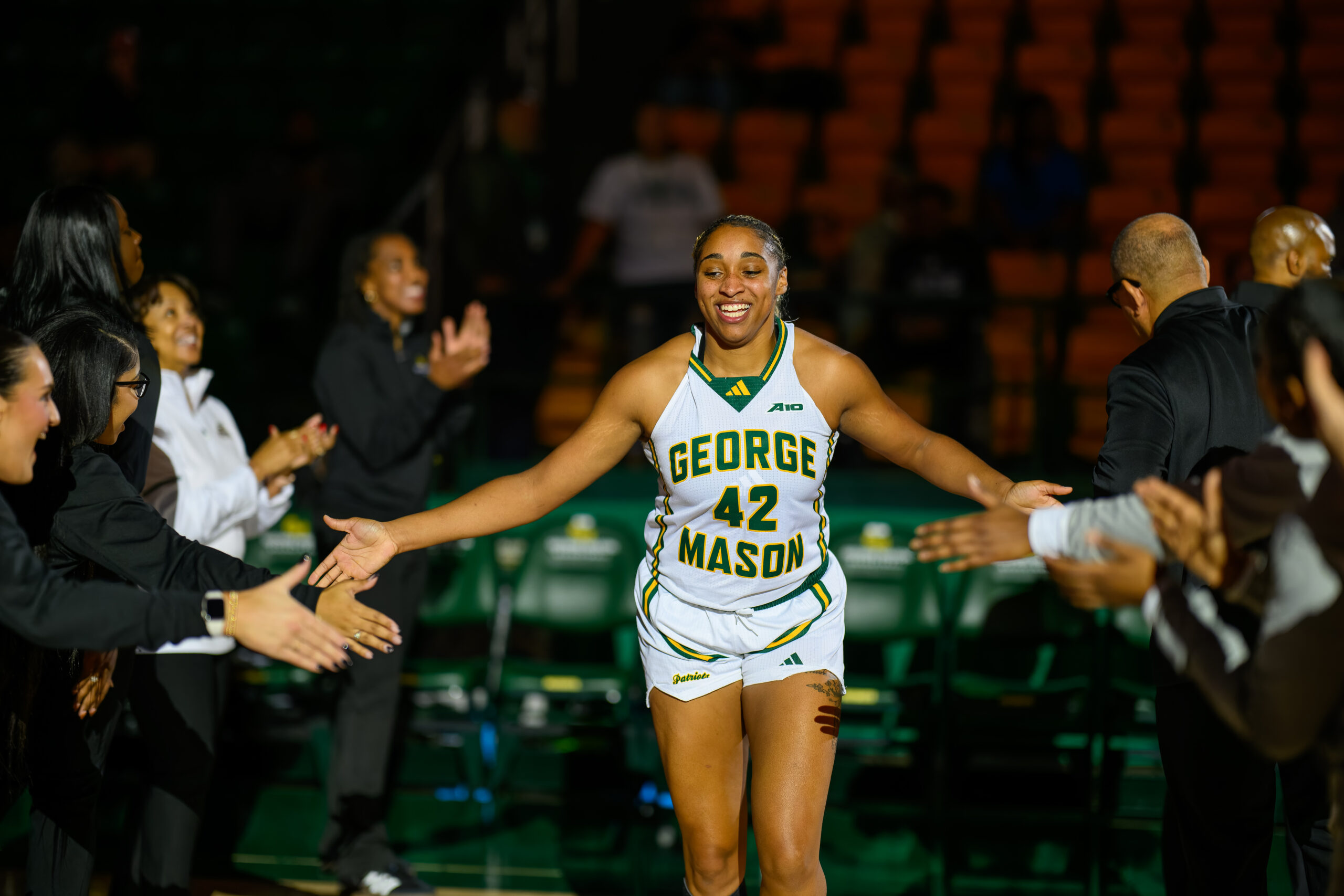 George Mason forward Nalani Kaysia stretches out both arms to high-five her teammates and coaches as her name is announced during player intros.