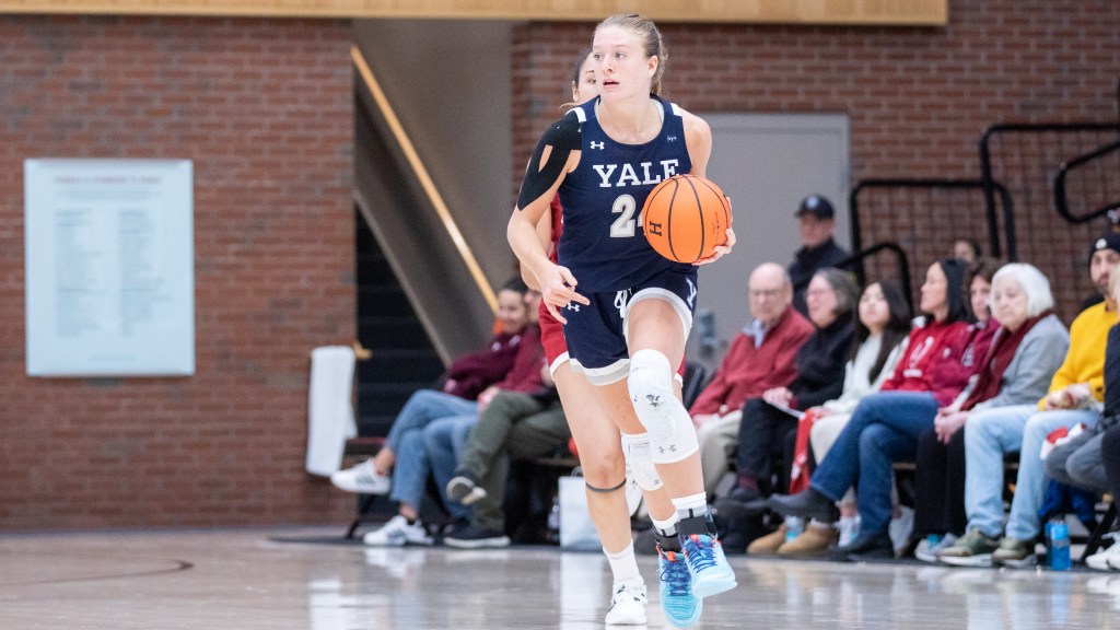 Yale forward Mackenzie Egger dribbles the ball up the court with her left hand and looks to her right.
