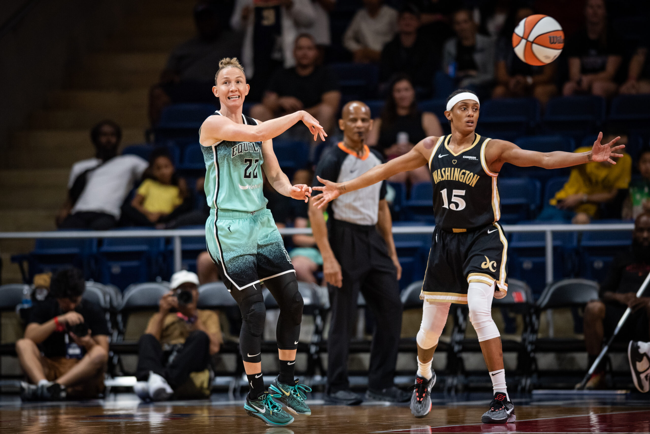 New York Liberty guard Courtney Vandersloot does a no-look pass while Washington Mystics guard Brittney Sykes watches with arms outstretched