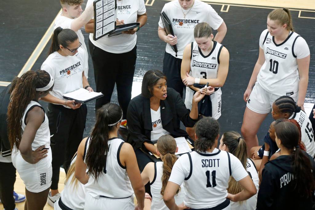 Providence head coach Erin Batth sits during a huddle and talks to her team.