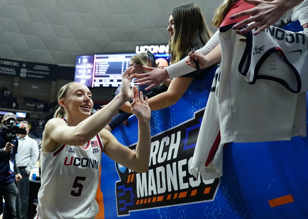 Paige Bueckers high-fives fans at Gampel Pavilion as she walks toward the tunnel.