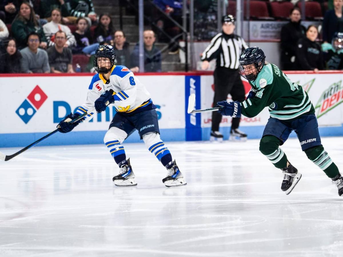 Saulnier (right in green) skates hard at the puck, as Flanagan (left in white) also pursues the puck.