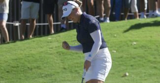 Manon De Roey moves toward the hole with her putter in her hand and her other hand in a fist, celebrating.