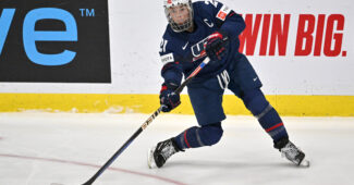 Hilary Knight, wearing Team USA jersey, shoots the puck