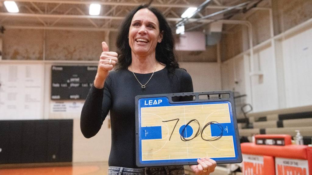 Lisa Gedaka holds a basketball clipboard with the number 700 written on it