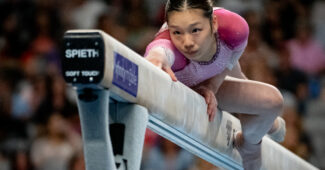 Katelyn Jong wears a pink and white leotard for a routine on balance beam.