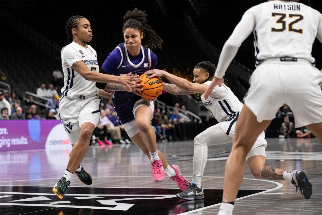 Kansas State Wildcats guard Zyanna Walker attacks down the middle of the lane while West Virginia guards JJ Quinerly and Sydney Shaw reach in to try to take the ball away.