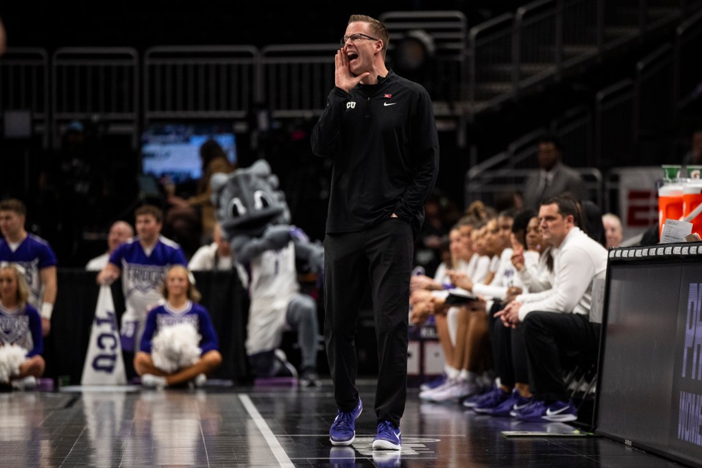TCU head coach Mark Campbell raises his right hand to his mouth and yells from the sideline.